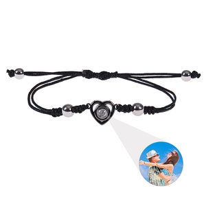 Detail of adjustable black braided bracelet with heart pendant and photo projection feature