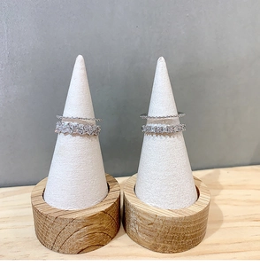 Detail view of stacked silver zircon petal rings on a white cone display stand