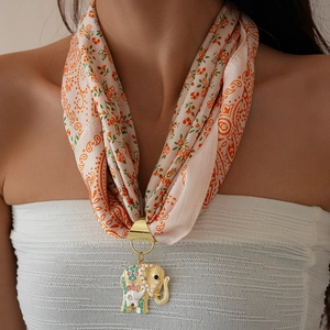 Detail of silk scarf with golden elephant pendant inlaid with pearls and crystals