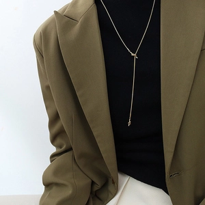 Minimalist long gold chain necklace with a knotted design detail worn by a model
