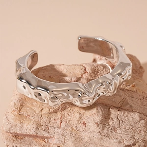Macro detail of silver geometric wrinkled cuff bracelet with wavy liquid texture finish