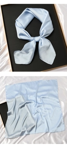 Detail of light blue silk square scarf showing smooth texture and elegant knotted style