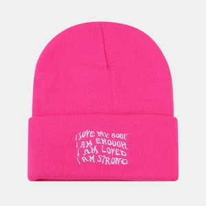 Close-up of hot pink ribbed knit beanie featuring white embroidered inspirational quotes