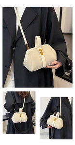 Close-up of a cream shell-shaped handbag featuring suede texture and gold metal hardware