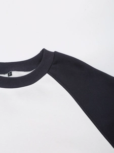 Detail showing neckline size tag M and black raglan sleeve stitching on white sweatshirt