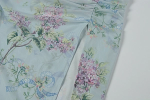 Dettaglio del tessuto mesh a fiori con arricciatura laterale e spacco sul vestito