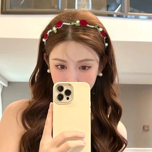 Close-up of a floral headband with red roses and white pearls on a gold wire