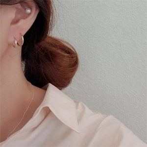Detailed view of simple 925 sterling silver gold hoop earrings and pearl studs on model