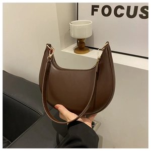 Close-up of a dark brown crescent underarm bag in smooth PU leather with gold hardware