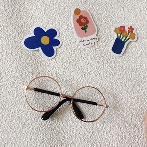Detail of rose gold round frame pet sunglasses on a beige textured background