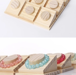 Detail of wooden bracelet display stand showing natural texture and beveled slots for jewelry
