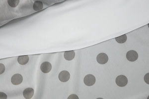 Détail du tissu en maille à pois blancs superposé sur une texture textile unie