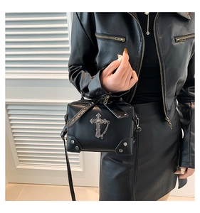 Detail of black gothic Y2K crossbody bag with large vintage metal cross and stud accents