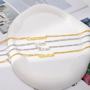 18K gold and silver zodiac nameplate necklaces on Figaro chains over a white tray