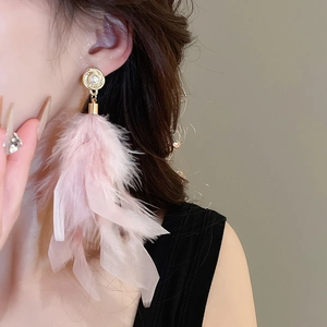 Detailed view of pink feather tassel earrings with gold pearl stud on a model