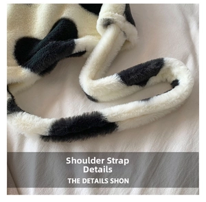 Detailed close-up of wide plush shoulder strap featuring black and white cow print texture