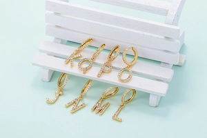 Detail of various gold letter charms K Q P O J N M L with sparkling cubic zirconia inlay