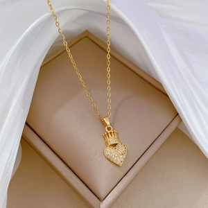Elegant gold crown heart necklace with shimmering crystals on white silk background