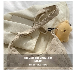 Detail of adjustable woven shoulder strap with silver buckle and yellow plush charm