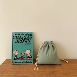 Close-up of light green drawstring cotton linen bag on wooden surface with books