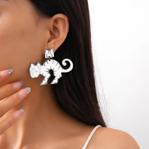 Detail of silver cat-shaped enamel earrings worn by a model showing cute cartoon style