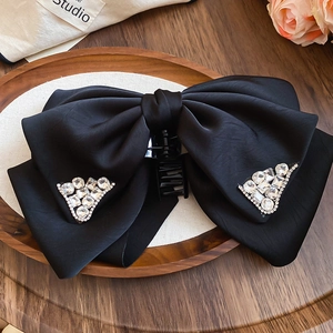 Detailed view of luxury black satin bow hair claw clip with sparkling rhinestones decoration