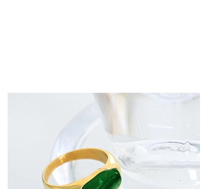 Close-up of a gold-plated snake ring featuring a rectangular emerald green gemstone