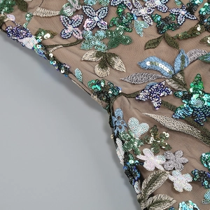 Detail shot of intricate floral embroidery and shimmering sequins on brown mesh fabric