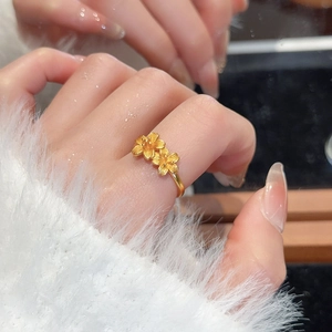 Detailed view of dual 24k gold floral rings with brushed texture on adjustable band