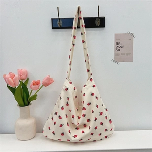 Détail de la texture d'un sac cabas en velours côtelé à fraises sur un mur minimaliste