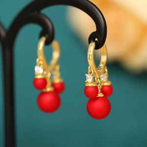 Macro view of gold heart stud and red matte Mickey-shaped bead tassels earrings