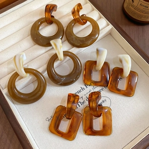 Macro shot of amber tortoise shell resin earrings in a beige jewelry display box