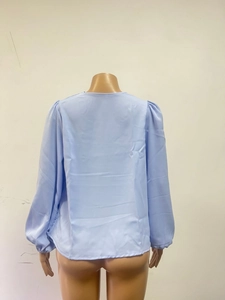 Detail view showing back texture of light blue chiffon long sleeve blouse on a mannequin
