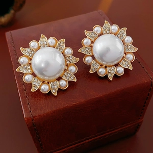 Macro shot of floral pearl stud earrings with sparkling crystals on leather jewelry box