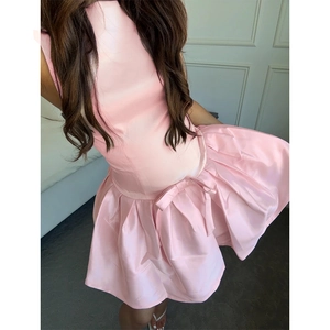 Close-up detail of pink satin dress featuring waist bow decoration and slim fit texture
