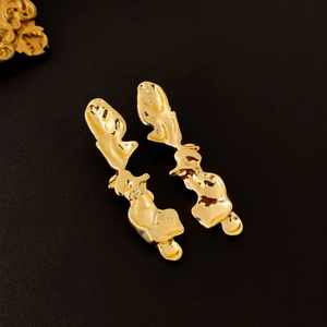 Gros plan détaillé de boucles d'oreilles dorées forme lave au design asymétrique