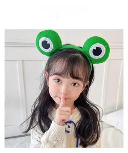 Detail of green plush frog headband with cute 3D eyes on a child model's head