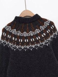 Dettaglio del motivo a maglia Fair Isle su maglione grigio scuro con dettagli bianco e marrone