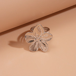 Détail d'une bague fleur argentée aux pétales métalliques sur un support épuré