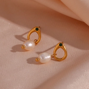 Detail showing gold earrings with freshwater pearls and green stones on silk