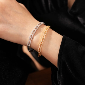 Close-up of gold and silver pavé zircon oval link bracelets with hollow cross patterns