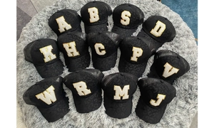 Macro view of distressed black trucker hats with gold glitter and sequin letter patches