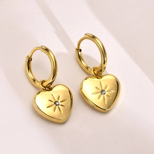 Detail view of gold hoop earrings with heart charms and a sparkling starburst center