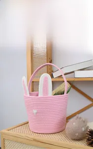Detail view of pink cotton rope Easter basket with bunny ears and bow on a shelf