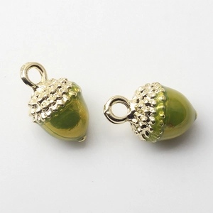 Detail of golden acorn charms with green resin and metal texture for DIY jewelry