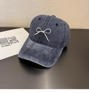Détail de la casquette de baseball en denim lavé bleu foncé avec nœud brodé blanc élégant