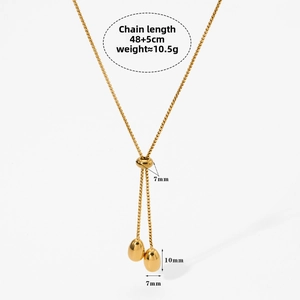 Close-up of golden adjustable Y-necklace showing bead chain, slide clasp and egg-shaped charms