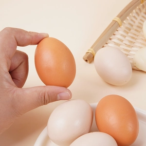 Realistic artificial egg models in brown and beige tones displayed in a bamboo basket