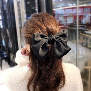 Close-up of a large black satin bow hair clip worn on the back of a woman's head