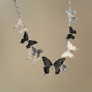 Detail view of colorful oil-dripped butterfly charms on a silver link chain necklace